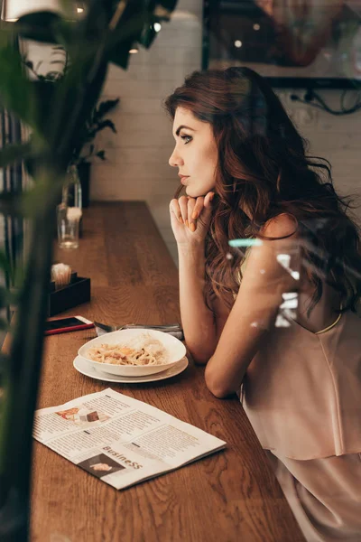 Vista laterale della donna premurosa seduta a tavola nel caffè — Foto stock