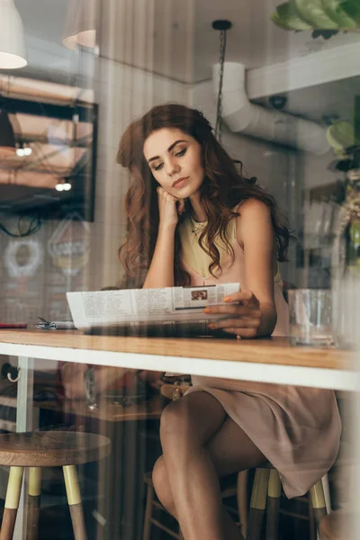 Portrait de jeune femme lisant un journal dans un café — Photo de stock