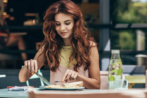 Retrato de una joven almorzando sola en el restaurante - foto de stock