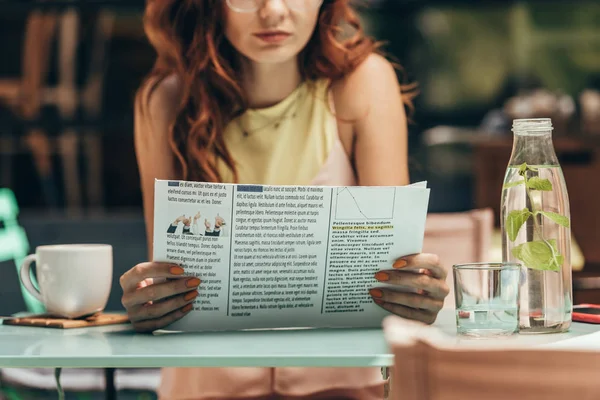 Vista parcial de la mujer leyendo el periódico en la cafetería - foto de stock