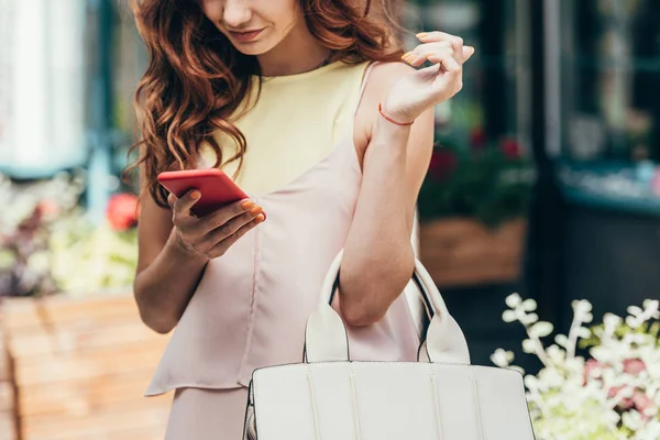 Partial view of stylish woman using smartphone on street — Stock Photo