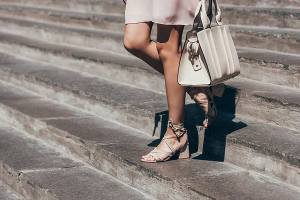 Partial view of woman in stylish shoes walking down steps on street — Stock Photo