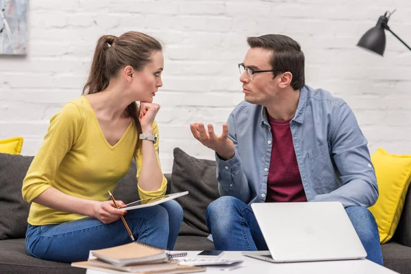 Couple adulte de pigistes se disputant pendant le travail sur le canapé à la maison ensemble — Photo de stock