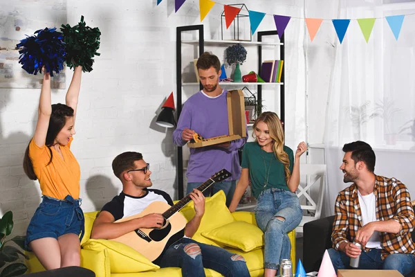 Jóvenes amigos con pizza, cerveza y guitarra se divierten juntos en la fiesta en casa - foto de stock