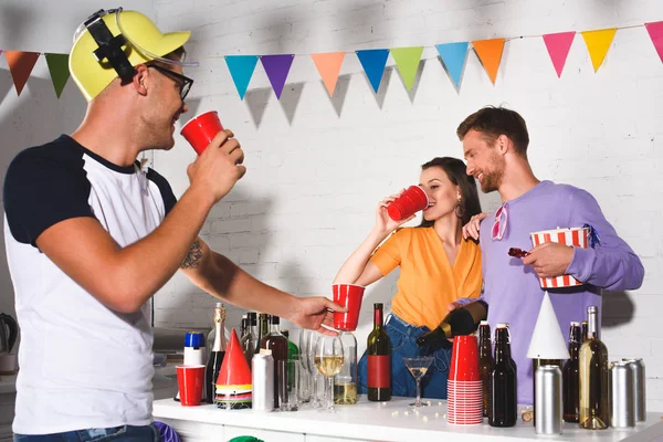 Счастливые молодые друзья пьют алкоголь и тусуются вместе дома — стоковое фото