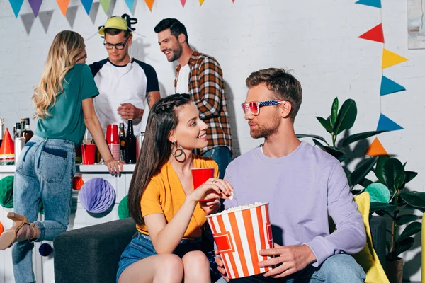 Giovane uomo e donna che si guardano mentre bevono birra e mangiano popcorn a casa festa — Foto stock