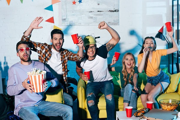Aufgeregte junge Freunde trinken Bier und essen Snacks auf der Heimparty — Stockfoto