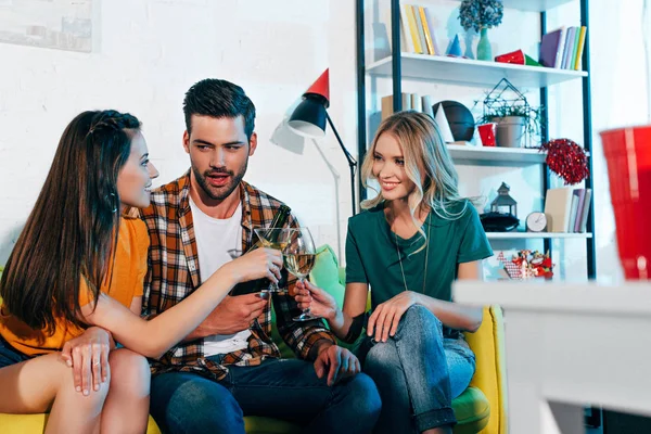 Jovem bonito bebendo vinho com meninas bonitas na festa em casa — Fotografia de Stock