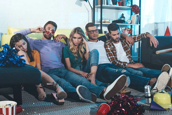 Пьяные молодые люди сидят на полу после домашней вечеринки — стоковое фото