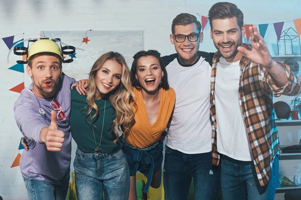 Cheerful young male and female friends smiling at camera at home party — Stock Photo