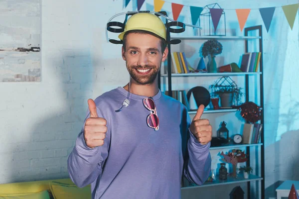 Young man in beer hat showing thumbs up and smiling at camera — Stock Photo