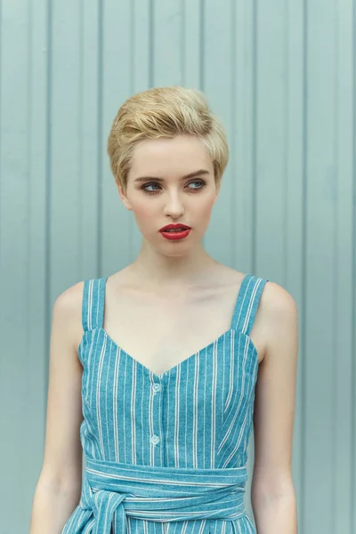 Молода жінка з коротким волоссям позує в модній блакитній сукні — стокове фото