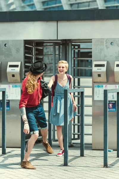Alegre pareja de turistas tomados de la mano en la estación de transporte público en la ciudad - foto de stock
