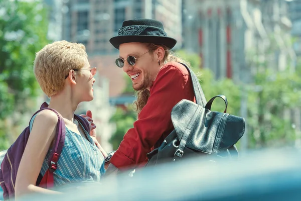 Hermosa pareja sonriente con mochilas en la ciudad - foto de stock
