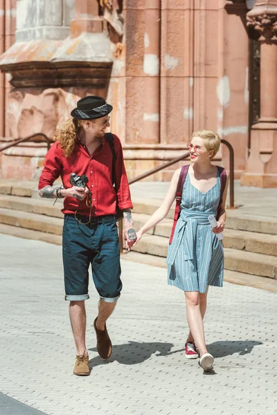 Pareja de turistas con cámara de mano y caminando por la ciudad - foto de stock