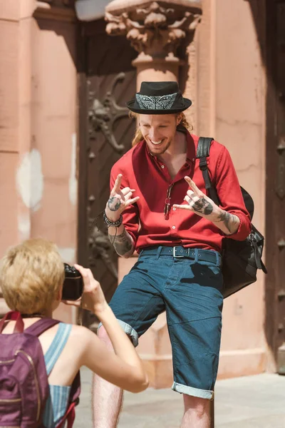 Woman taking photo of boyfriend showing rock signs — Stock Photo