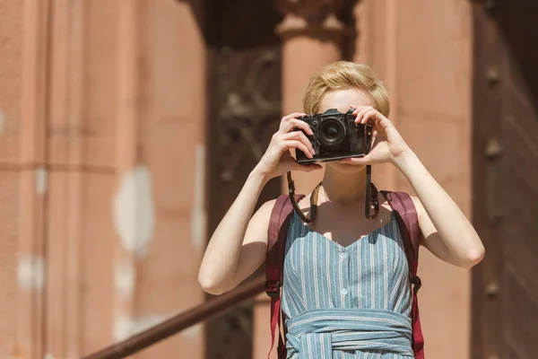 Girl with short hair taking photo on camera — Stock Photo