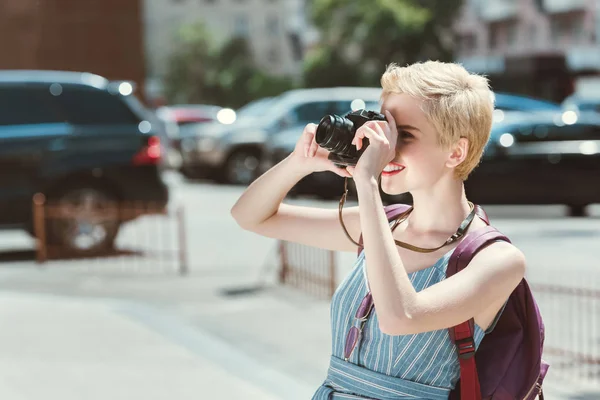 Traveler with backpack taking photo on camera in city — Stock Photo