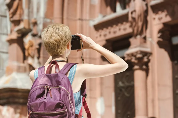 Vista trasera de turista con mochila tomando fotos en la ciudad - foto de stock