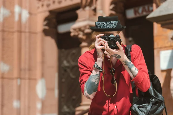 Татуированный мужчина с рюкзаком делает фото на камеру — стоковое фото