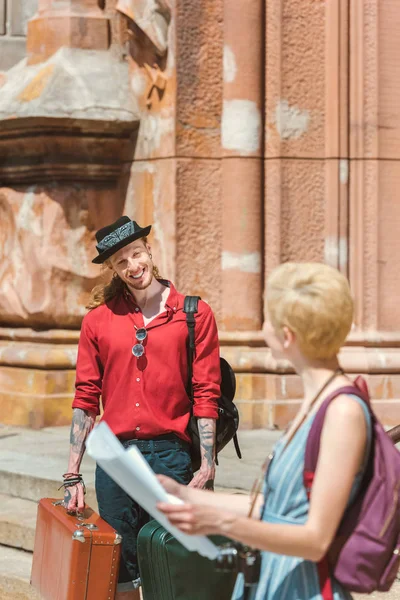 Couple of travelers with map, backpacks and retro suitcases in city — Stock Photo