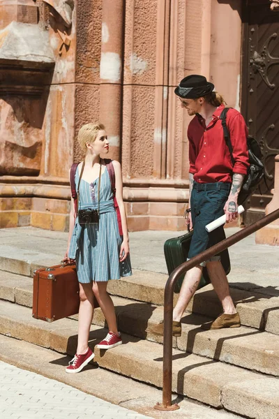 Couple of travelers with backpacks and retro suitcases in city — Stock Photo