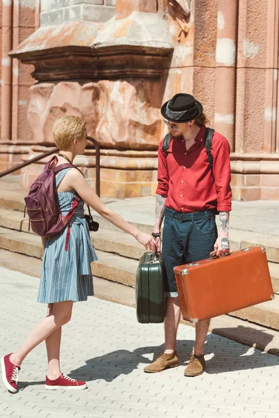 Pareja de viajeros con mochilas y maletas vintage en la ciudad - foto de stock