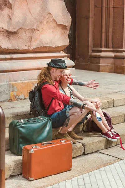 Couple of tourists with vintage travel bags sitting on stairs — Stock Photo