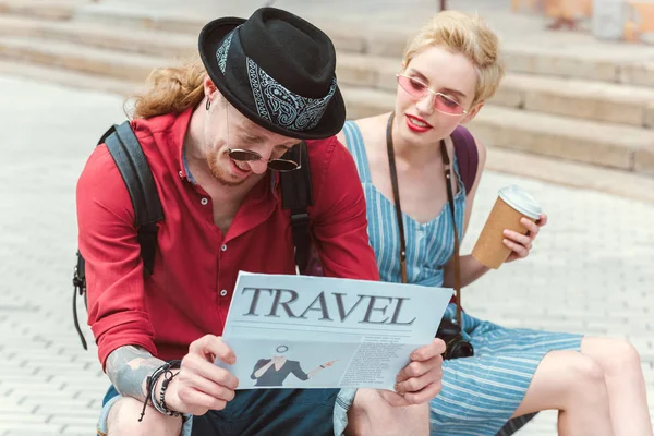 Stylish couple with travel newspaper and coffee to go — Stock Photo