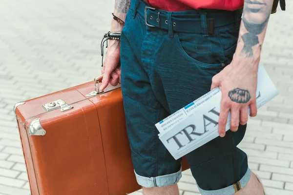 Partial view of man with travel newspaper and vintage suitcase — Stock Photo