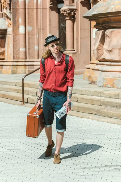 Турист с туристической газетой и винтажным чемоданом прогулка по городу — стоковое фото