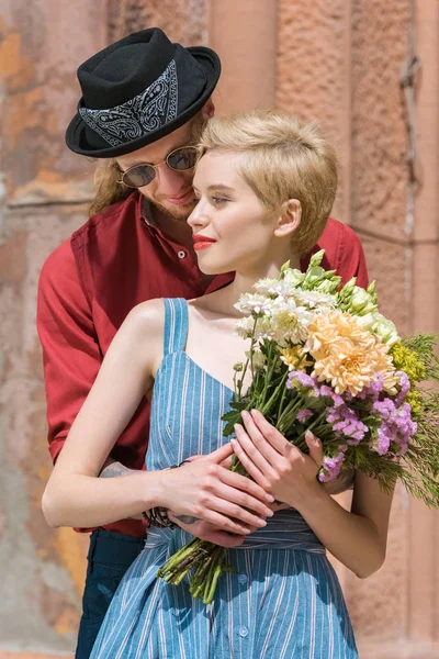 Beautiful couple with flowers hugging on romantic date — Stock Photo