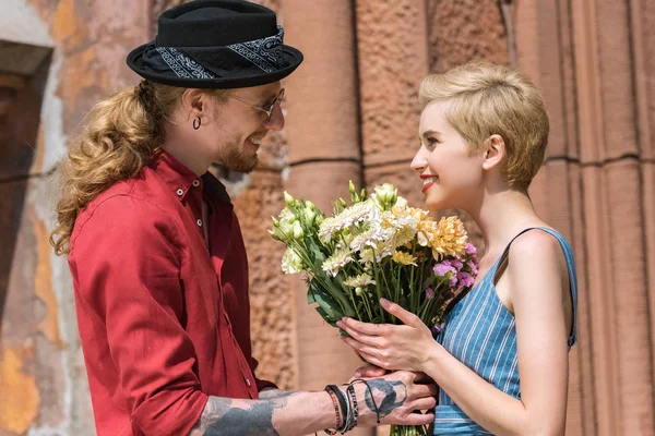 Sonriente pareja con flores en romántico fecha - foto de stock