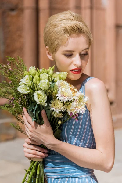 Attractive girl in trendy dress holding bouquet of flowers — Stock Photo