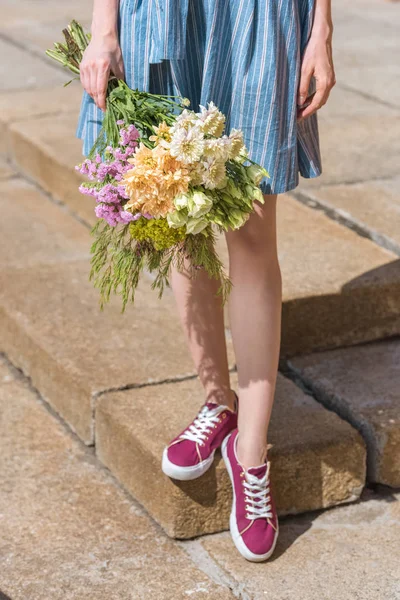 Cropped view of girl holding bouquet of flowers — Stock Photo