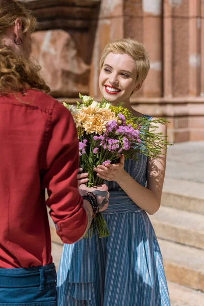 Cropped image of boyfriend presenting bouquet of flowers to girlfriend — Stock Photo