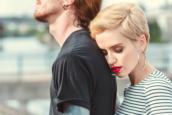 Immagine ritagliata di elegante fidanzata abbracciare fidanzato tatuato da dietro sul ponte — Foto stock