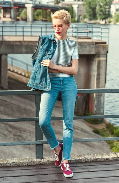 Élégant attrayant fille debout sur le pont en jeans et gilet en denim — Photo de stock