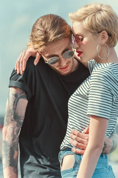 Boyfriend with tattoos and stylish girlfriend hugging on street — Stock Photo