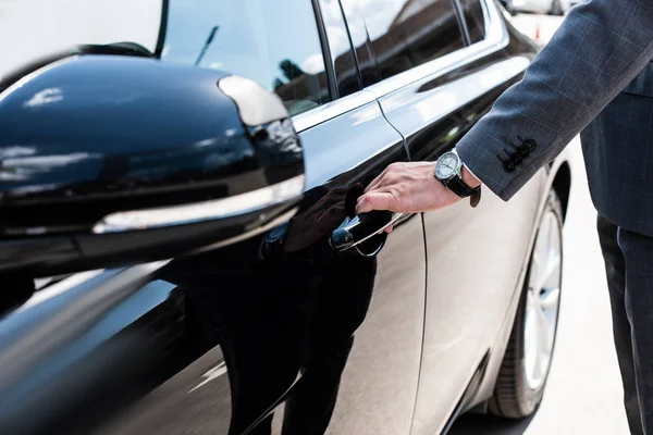 Частичный взгляд бизнесмена, открывающего дверь автомобиля — стоковое фото