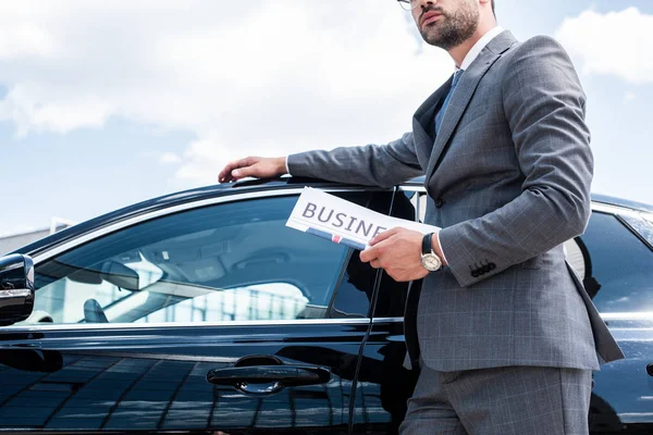 Частковий вид на бізнесмена з газетою, що стоїть на машині на вулиці — стокове фото