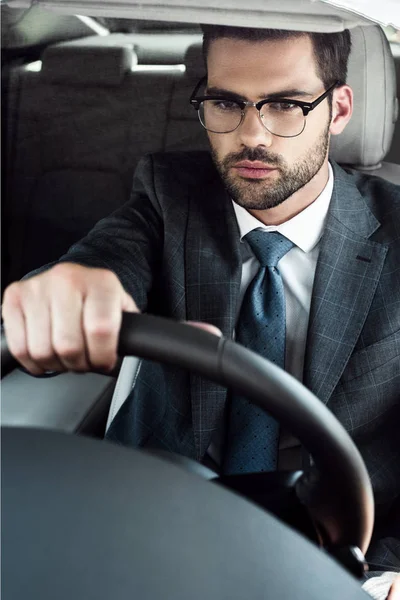 Retrato de homem de negócios em óculos dirigindo carro sozinho — Fotografia de Stock