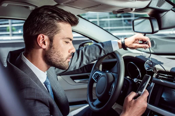 Vue latérale de l'homme d'affaires en utilisant un smartphone tout en conduisant voiture — Photo de stock