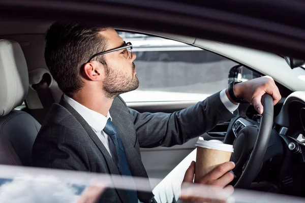 Vue latérale de l'homme d'affaires avec café pour aller voiture de conduite — Photo de stock