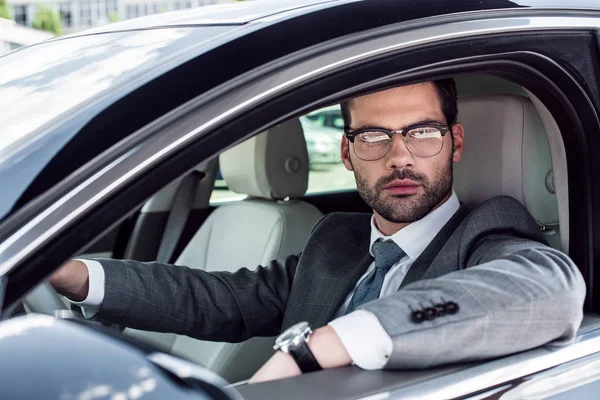 Portrait of businessman in eyeglasses driving car — Stock Photo