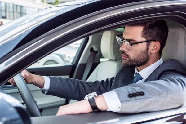 Side view of businessman in eyeglasses driving car — Stock Photo