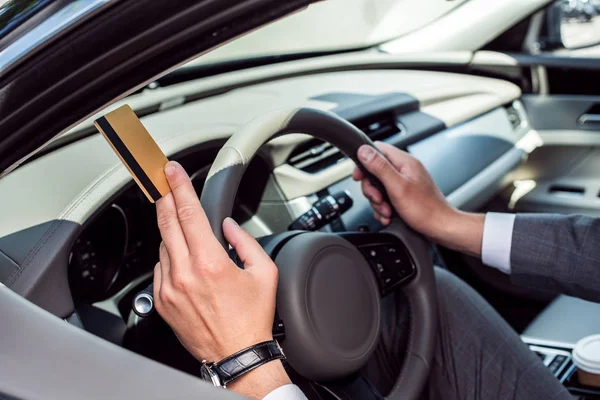 Teilansicht eines Geschäftsmannes mit Kreditkarte in der Hand, der im Auto am Steuer sitzt — Stockfoto