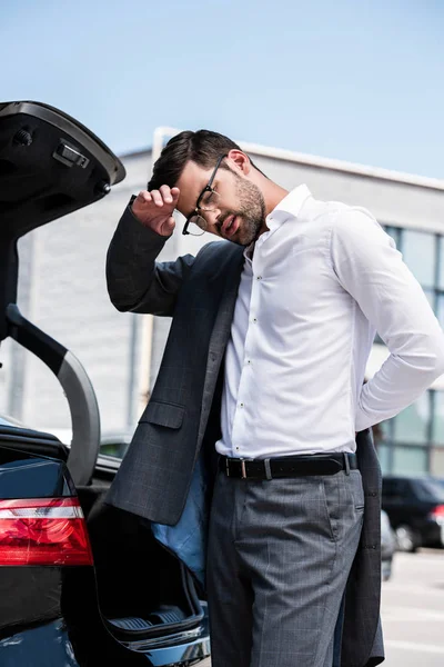 Low angle view of wiping forehead and taking off jacket near car at street — Stock Photo
