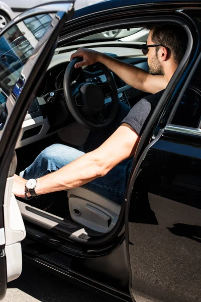 Vista lateral do homem elegante em óculos de sol fechando a porta de seu carro na rua — Fotografia de Stock