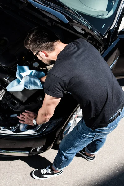 High angle view of young man in sunglasses checking car engine at street — Stock Photo